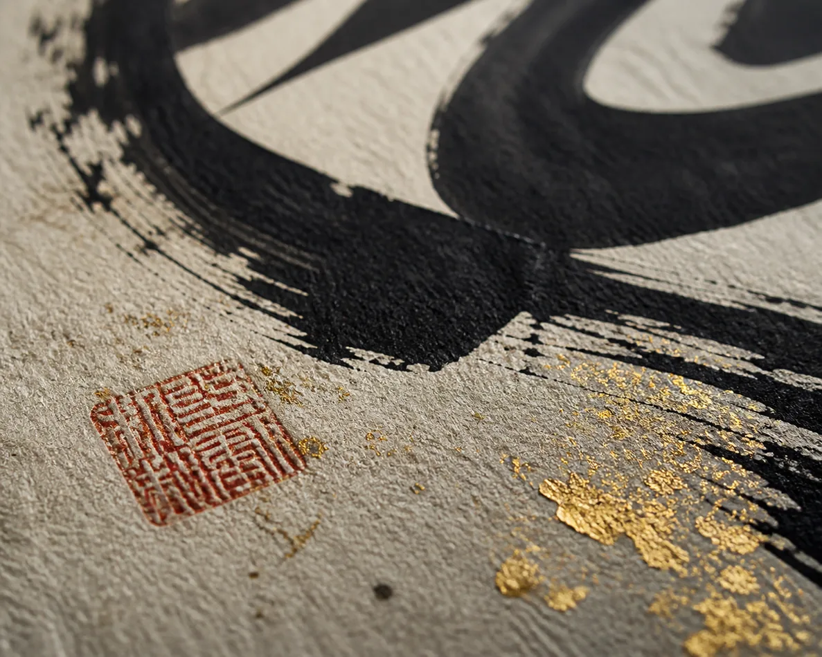 Macro detail of ink, paper texture, red seal, and gold flecks